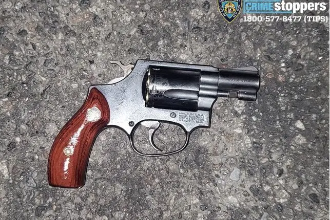 A revolver handgun photographed on a city street.